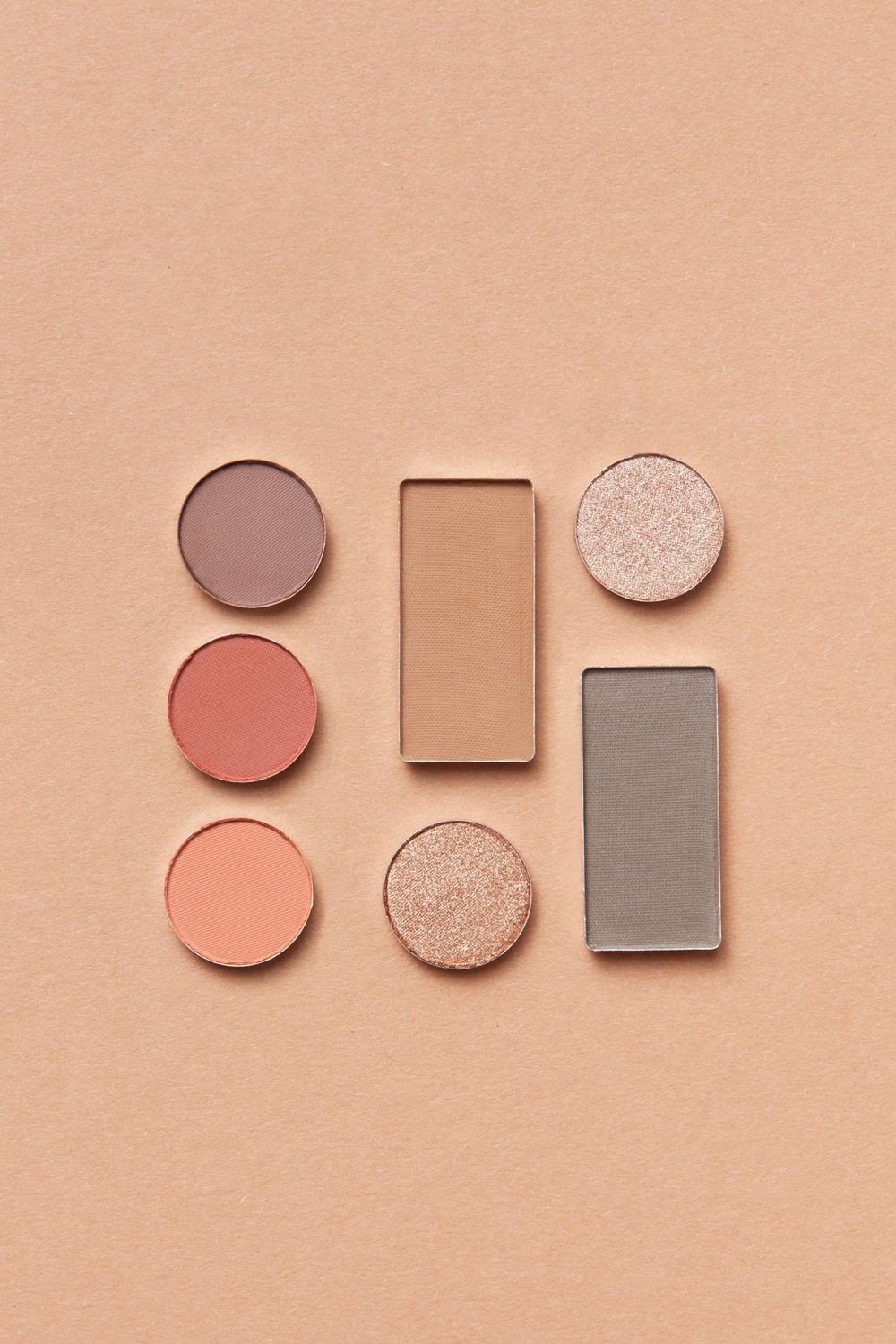 Different pressed makeup powders on an orange surface