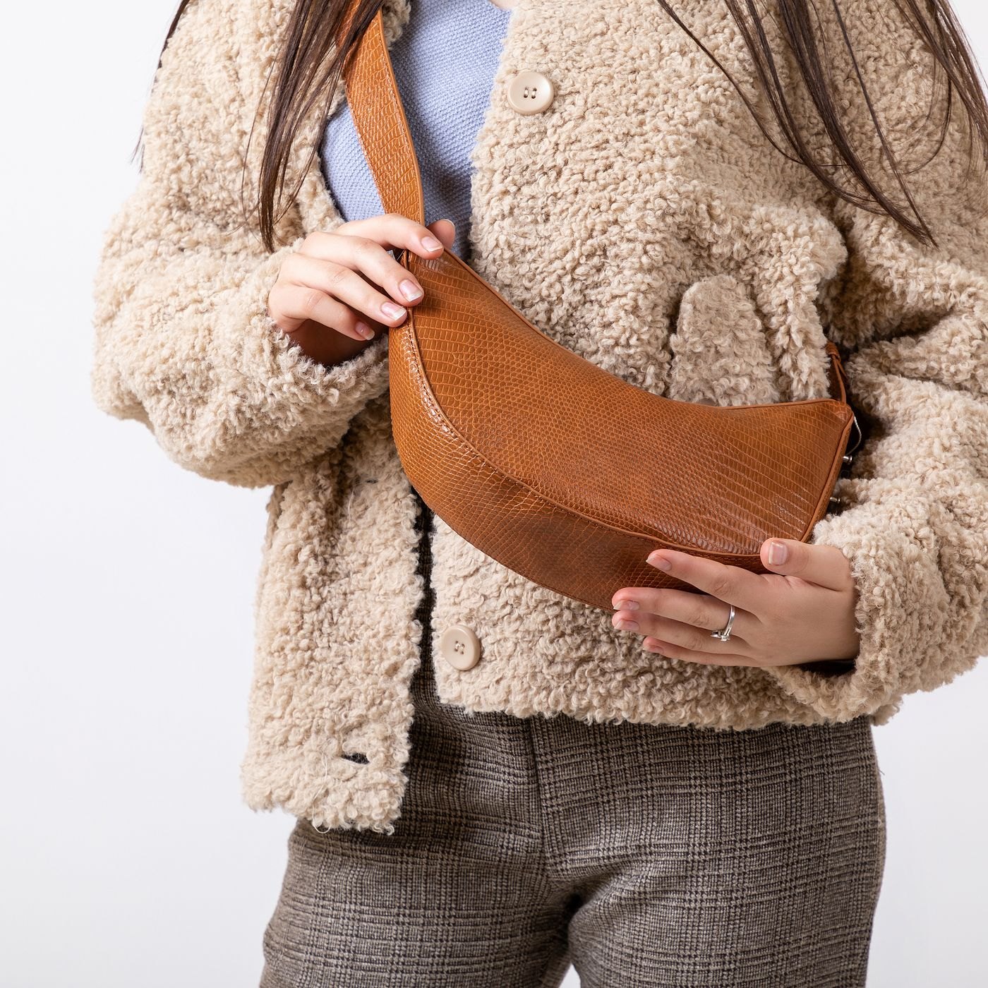 Brown crossbody bag worn over a coat