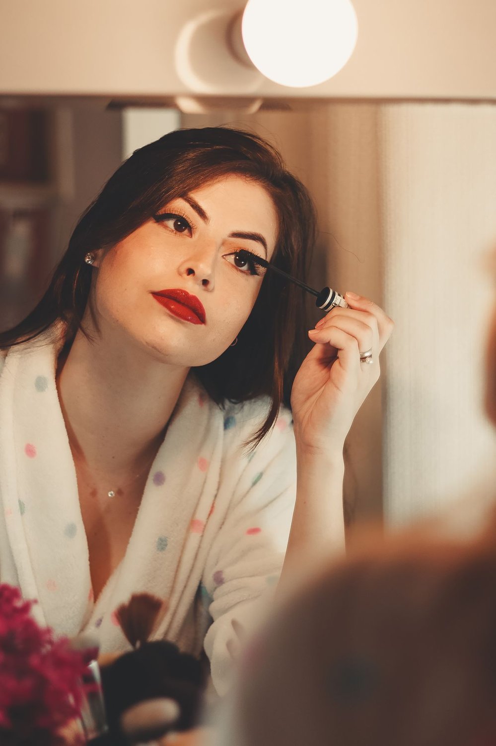 Woman applying makeup at a vanity mirror before going out