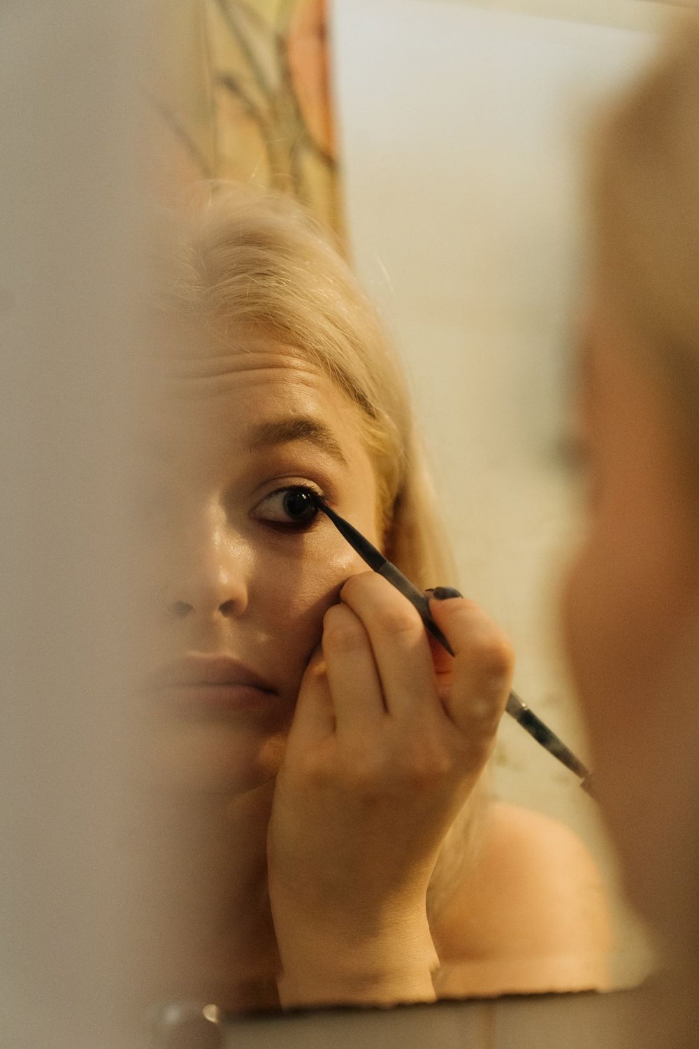 Woman applying eye makeup in front of a mirror