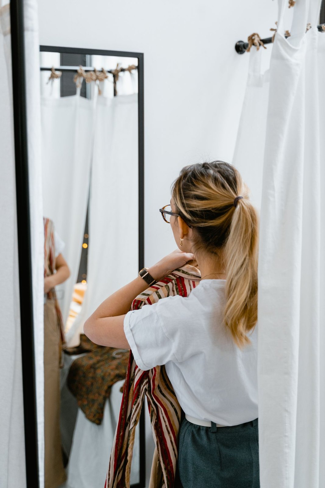 Woman checking a garment in a fitting-room mirror