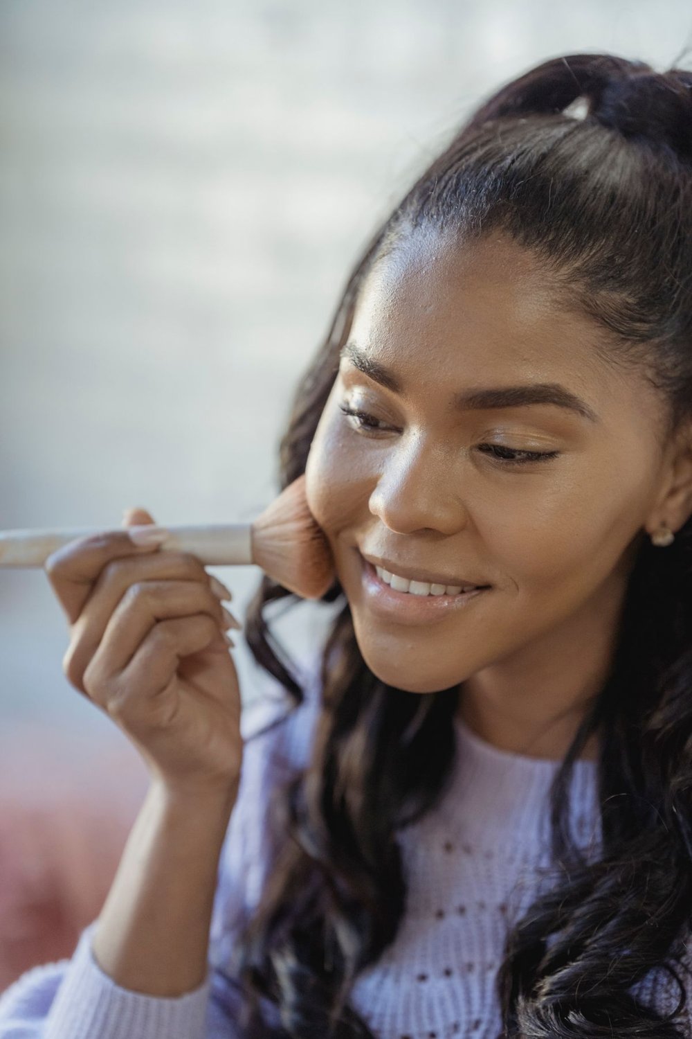 Woman applying makeup with a brush at home