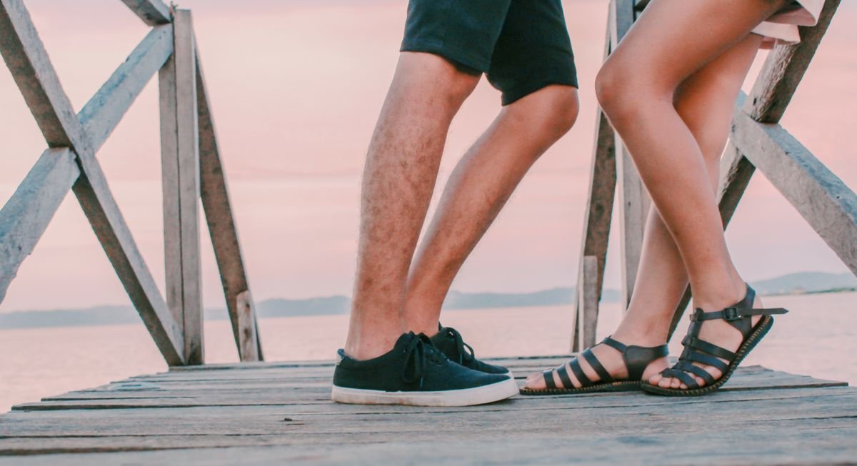 Flat strappy sandals and trainers worn on a wooden dock