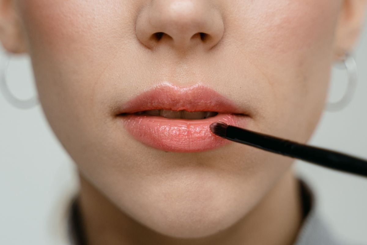 Close-up of pink lipstick being applied with a lip brush