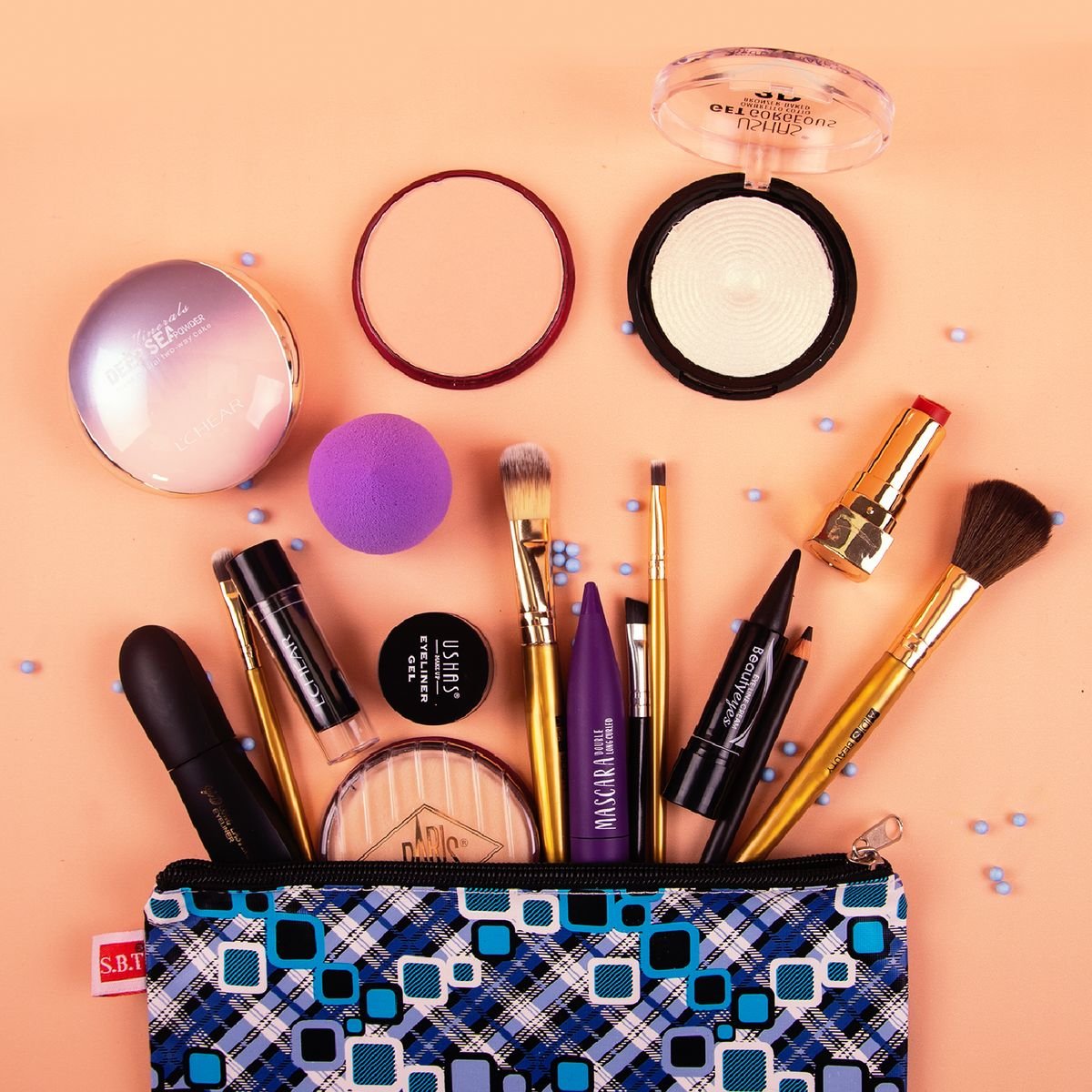 Open makeup pouch with cosmetics and brushes on a peach surface