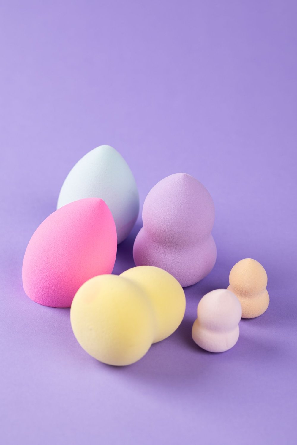 Makeup sponges in different shapes on a purple background