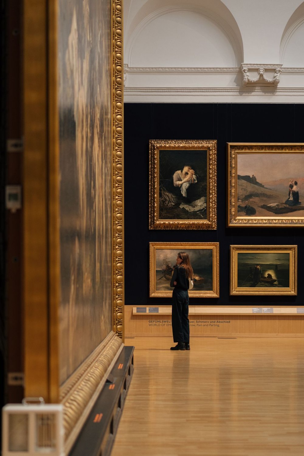 Visitor looking at paintings in a museum gallery