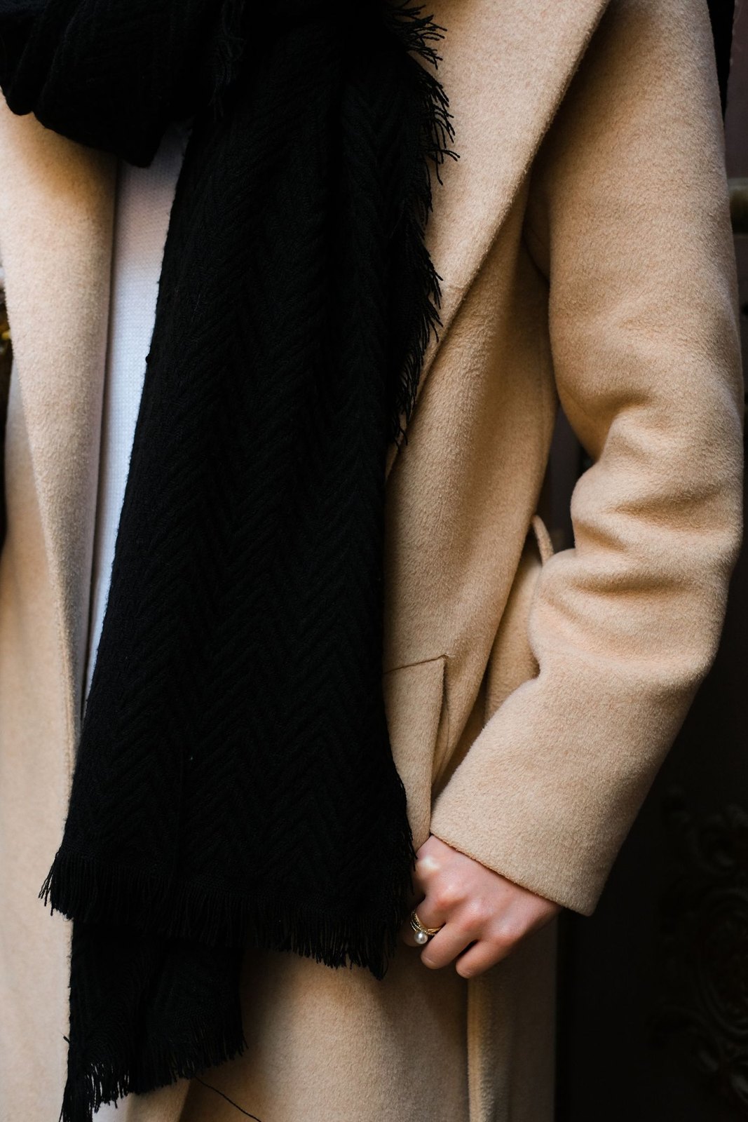 Dark scarf tucked into a beige coat