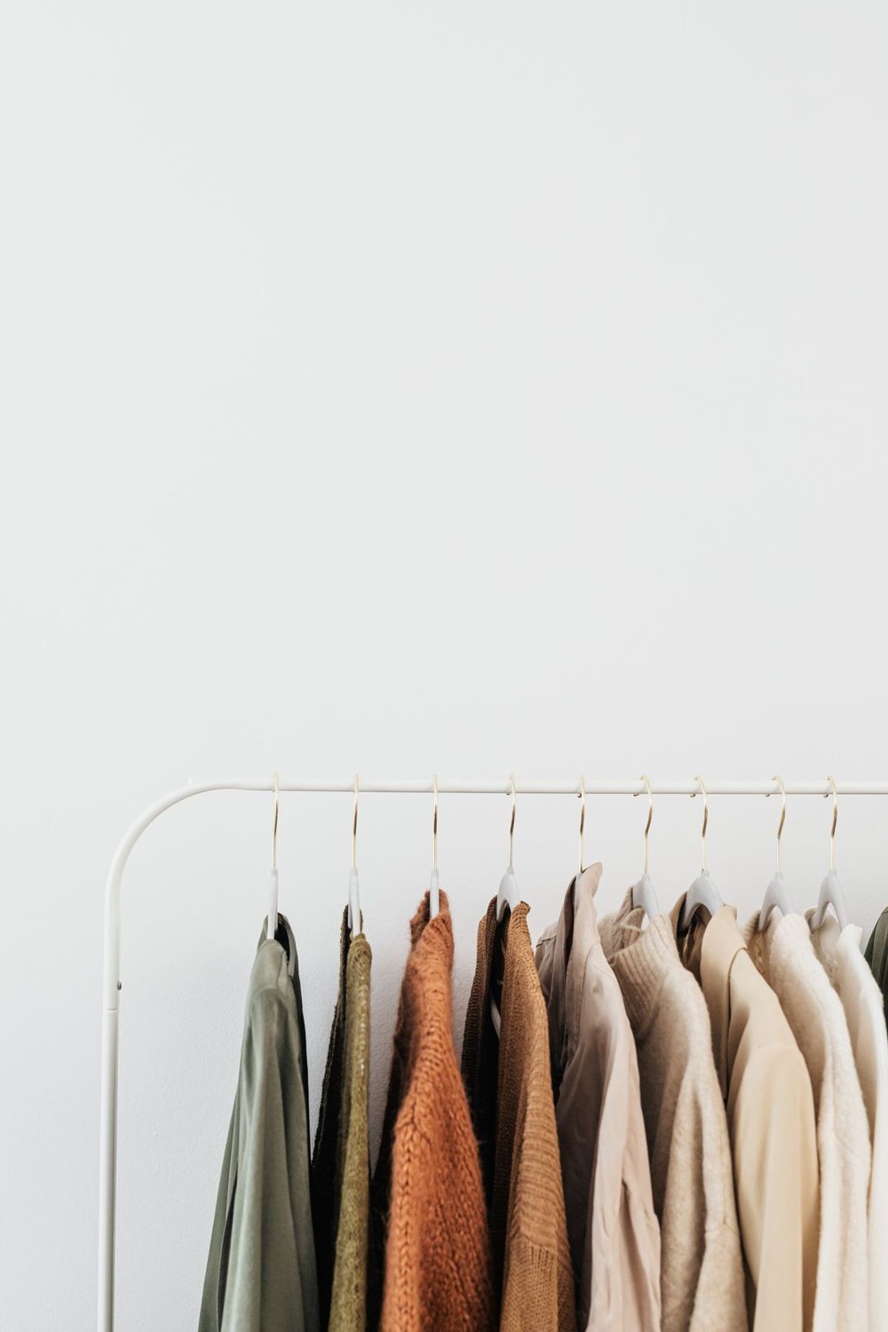 Neutral clothing arranged on hangers for a seasonal wardrobe