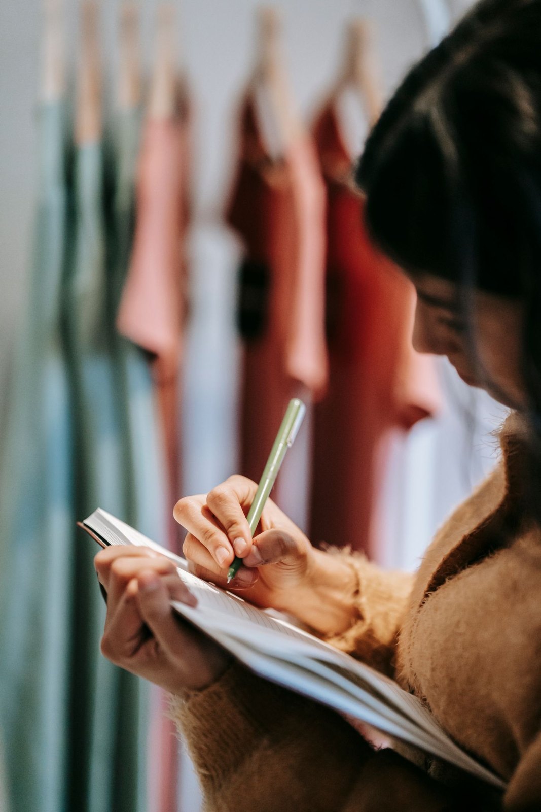 Notebook held beside a rail of clothes