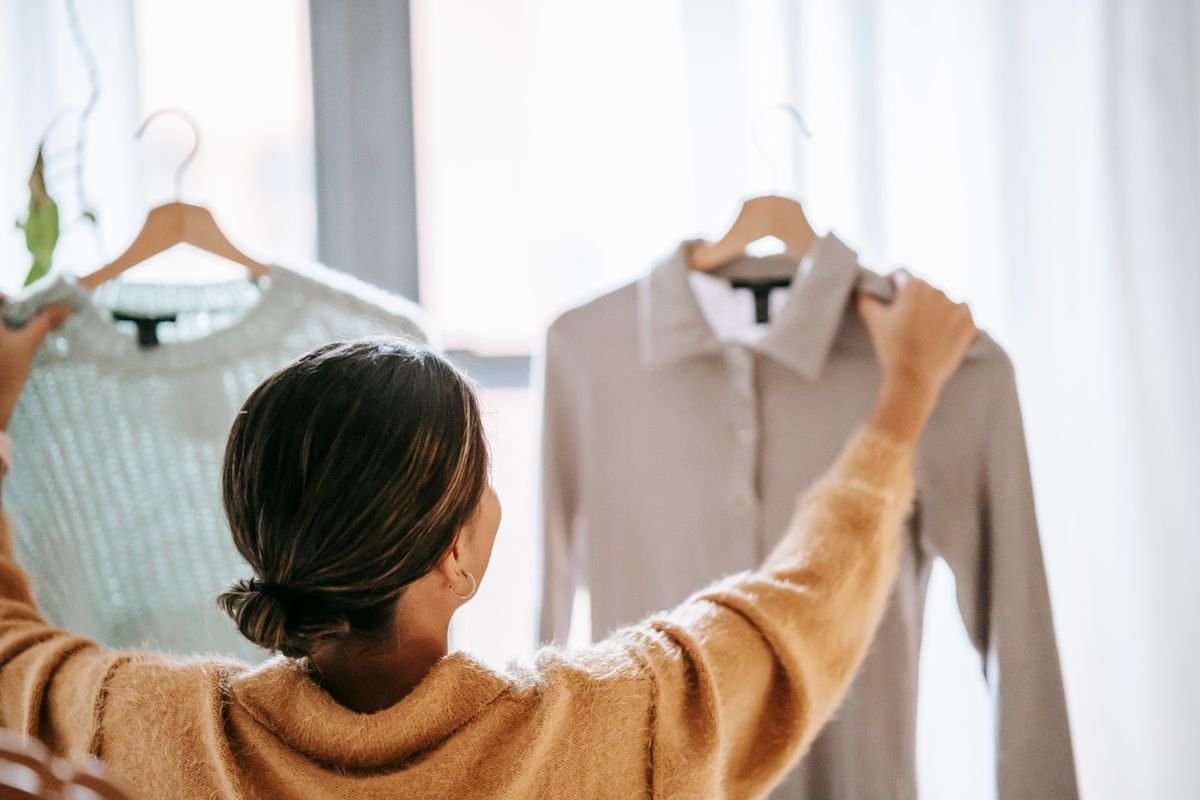 Shopper comparing clothes on hangers