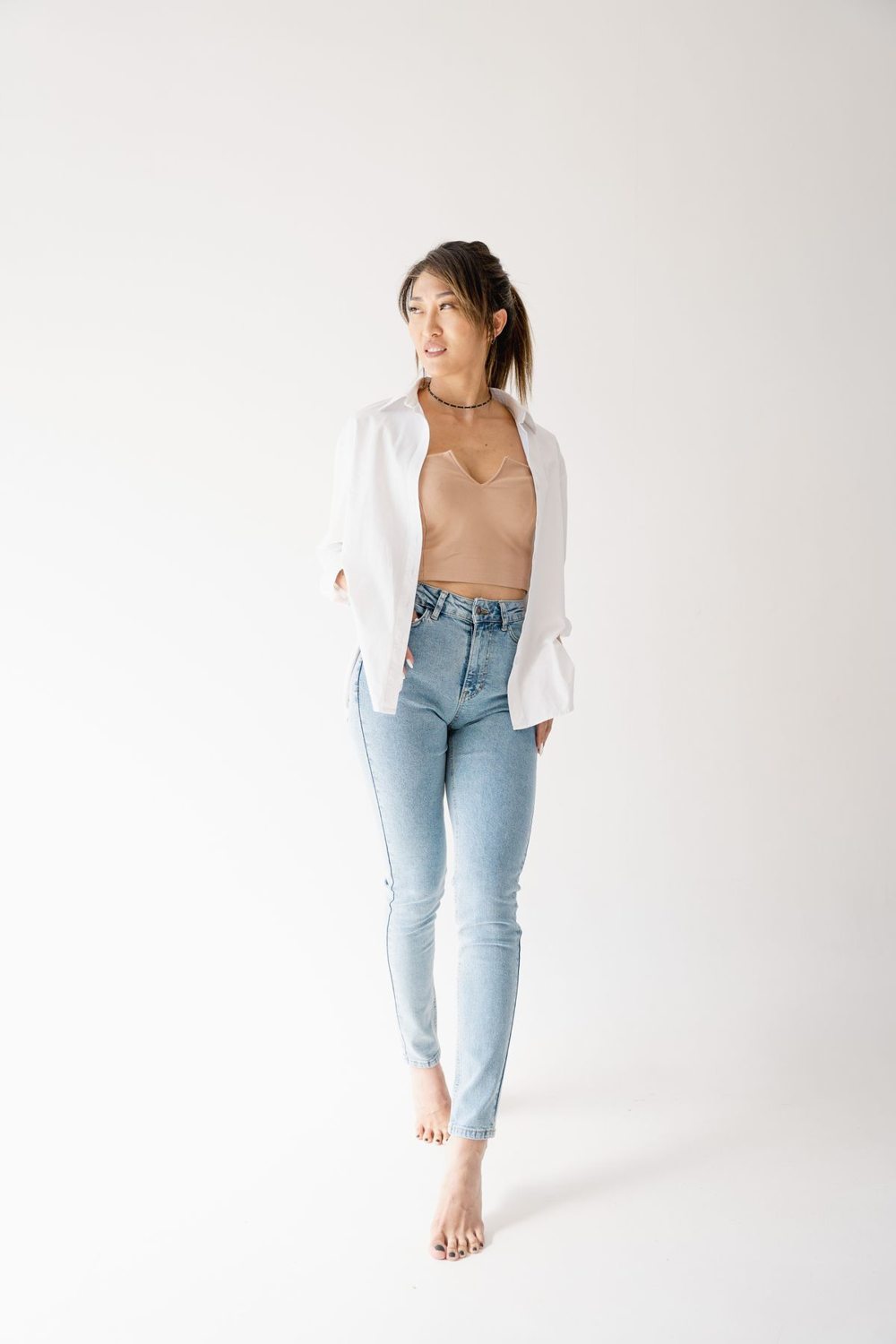 White shirt and straight-leg jeans against a plain backdrop