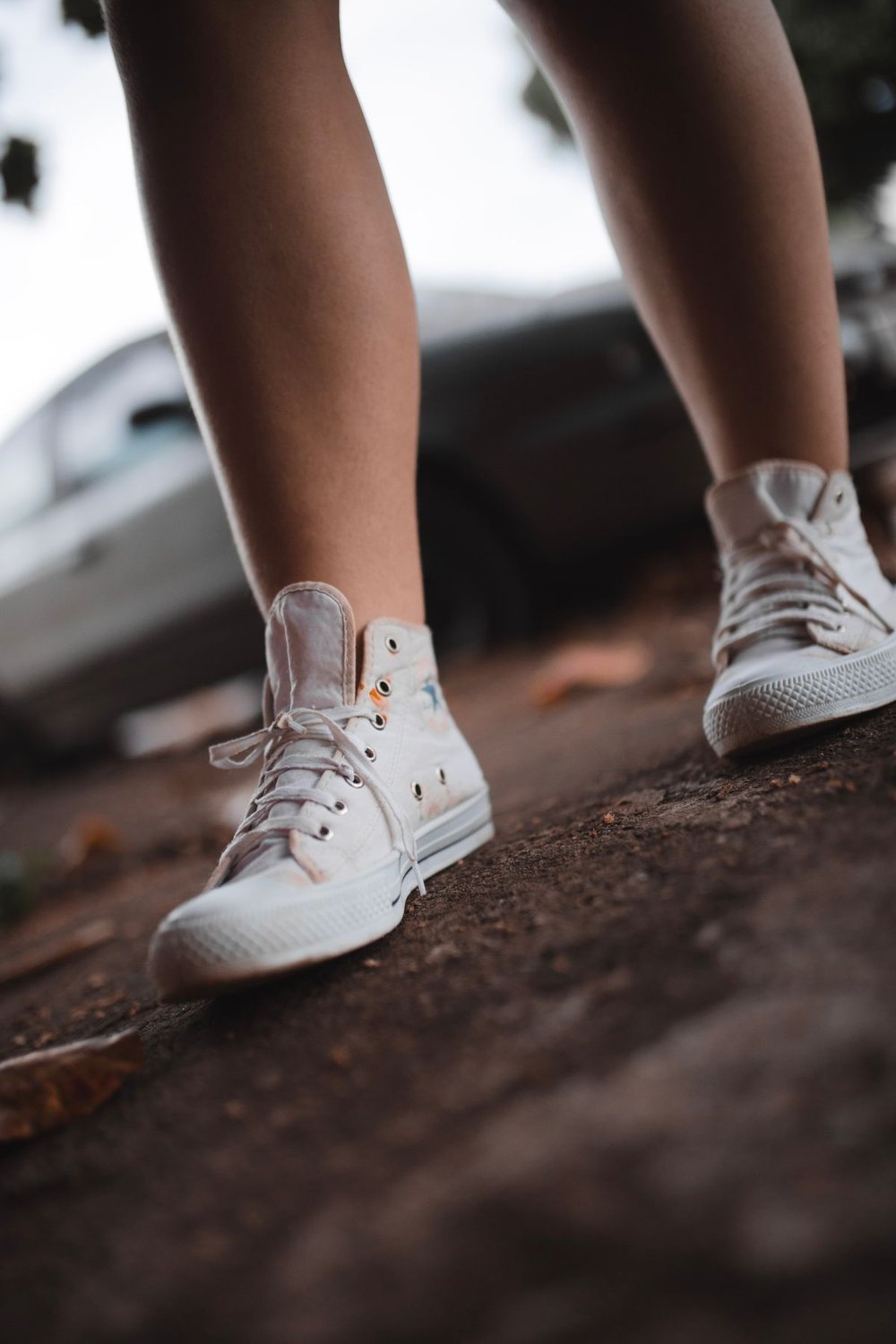 White high-top trainers worn on a city pavement