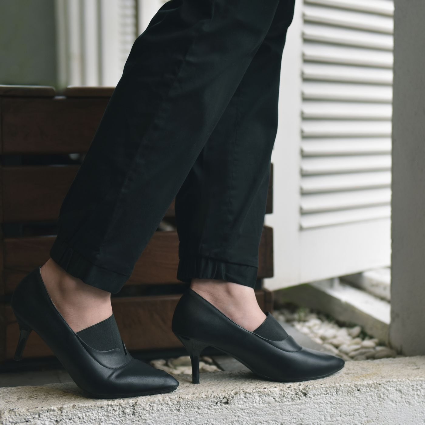 Black trouser hems meeting dark heeled shoes