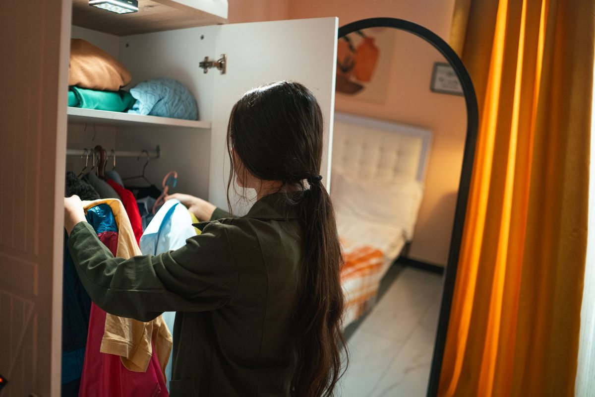 Woman organising clothes in a bedroom wardrobe