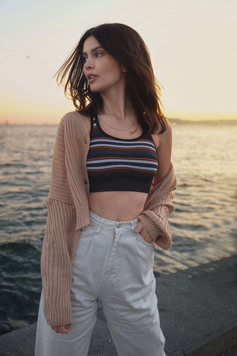 Woman wearing a light cardigan at the shore in evening light