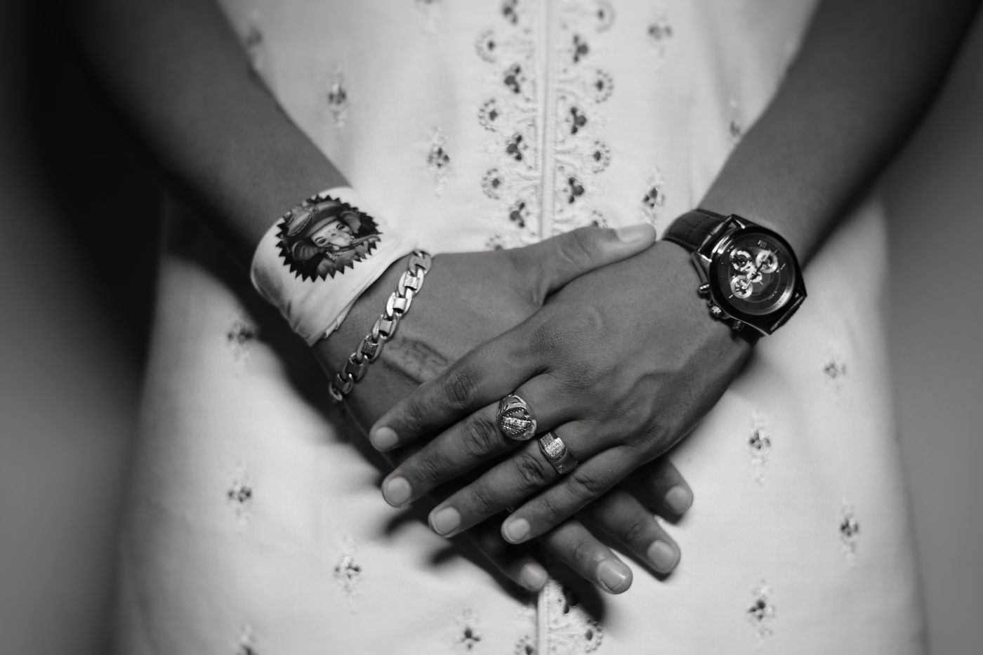 Hands wearing a wristwatch, bracelet and rings