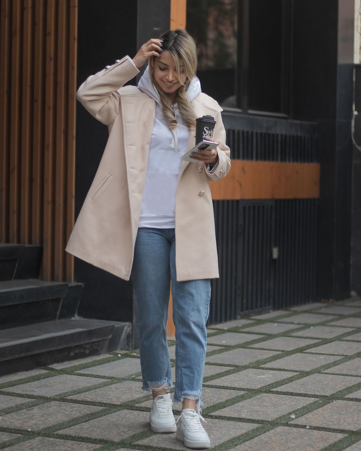 Coat layered over a hoodie and blue jeans on a city street